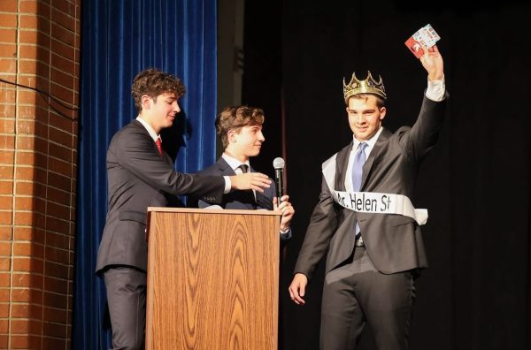 Evan Doyle lifts a Wawa gift card up high next to show hosts Jack Wall and Aiden Fairweather. Doyle was crowned Mr. Spiffy High.