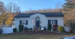 The Haunted House sits, shaded by surrounding trees. The second story was removed in the 1950s to fit in better with the surrounding houses.