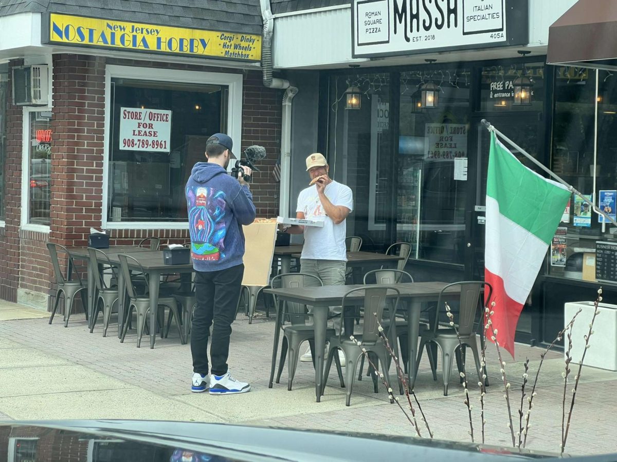 Dave+Portnoy%2C+seen+center+with+pizza+in+hand%2C+stands+outside+of+Massa+Roman+Square+Pizza+in+Scotch+Plains.+Portnoy+has+turned+his+hobby+of+rating+pizzas+into+a+lifestyle%2C+creating+a+worldwide+name+for+himself+online.