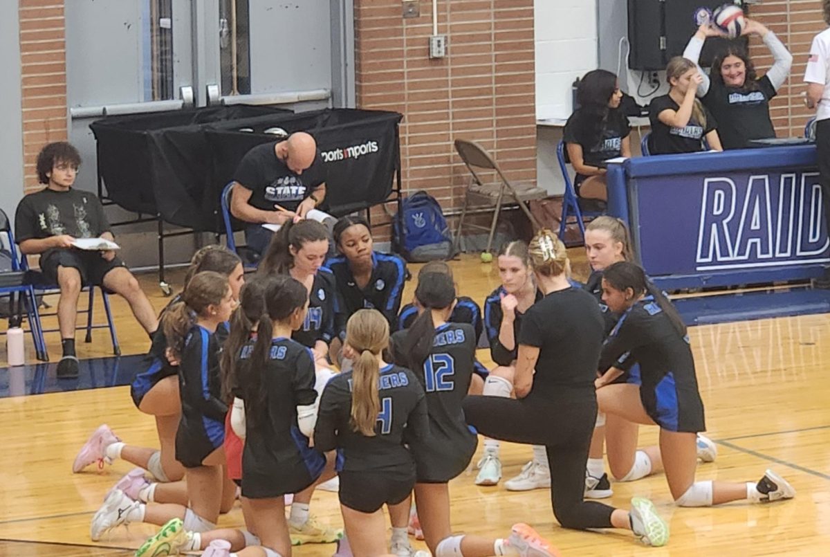 The SPF Girls Volleyball team kneels around head coach Adrienne Stack as they try to regroup during a timeout. The Raiders beat the Dayton Bulldogs 2-1 (26-28, 25-17, 25-16) on Thursday, Oct. 10, at Scotch Plains-Fanwood High School to improve their record to 13-5.