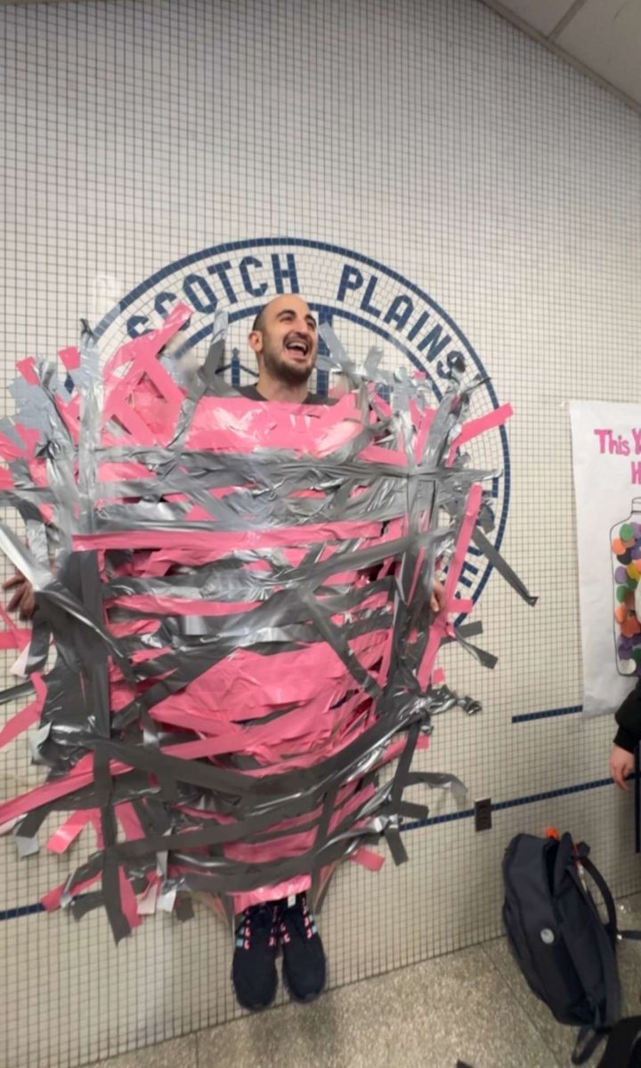 SMAC Advisor Mr. Fabiano duck taped to a wall to raise money for cancer research.
